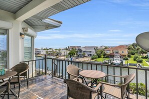 Ein Balkon mit Korbmöbeln und Blick auf eine Marina mit Booten.