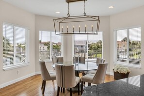 A dining area with a round table, six chairs, and a chandelier. - Waterfront Home Pool Golf Cart Dock Sleeps 16 (Destin)