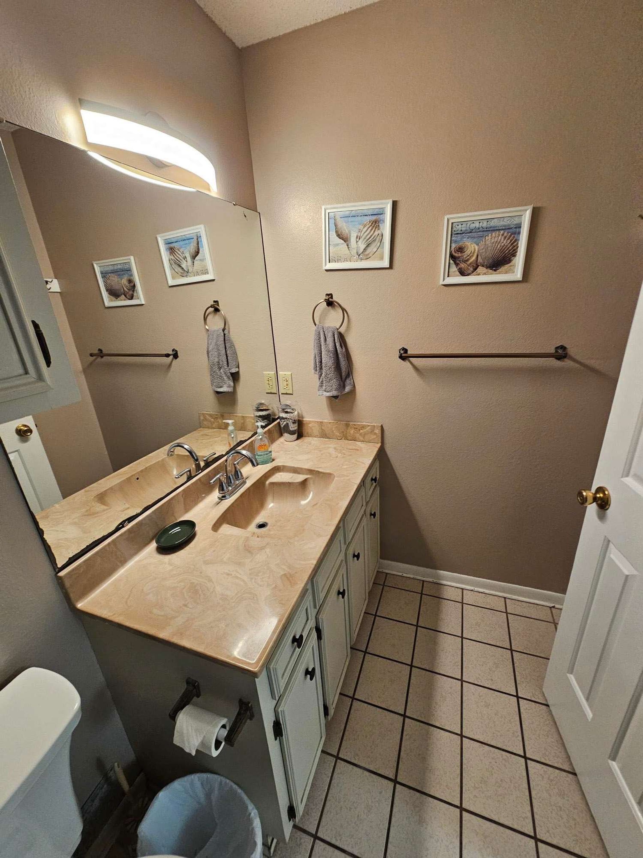 Een badkamer met een dubbele wastafel, een spiegel, een handdoekhouder en een toilet.