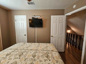 A bedroom with a bed, a television mounted on the wall, and two doors. - Padre Getaway- Fishing Dock Pool 2 Min to Beach (Corpus Christi)