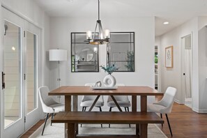 A dining area with a wooden table, white chairs, a hanging light fixture, and a mirror on the wall. - 1 5 Miles to Mizzou Spacious Updated Home (Columbia)