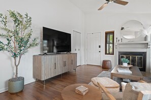 A modern living room with a flat-screen TV on a wooden cabinet, a large potted plant, and a fireplace with a mirror above it. - 1 5 Miles to Mizzou Spacious Updated Home (Columbia)