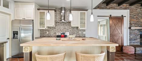 A kitchen with a central island, stainless steel appliances, and a stone backsplash.