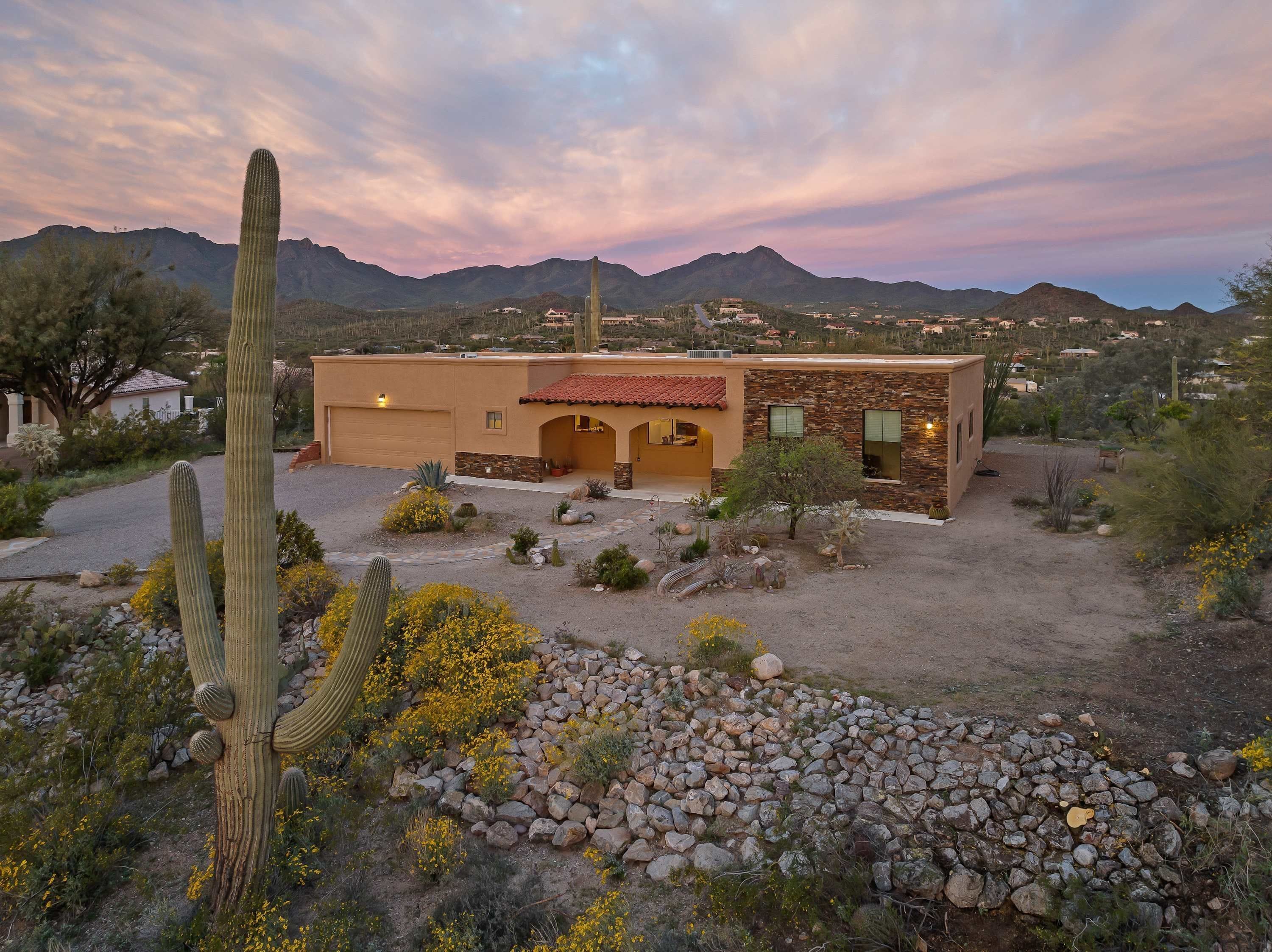 A desert-style house with a garage, a patio, and a view of mountains.