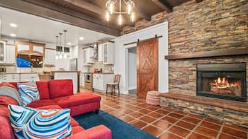 A spacious living area with a red sofa, a fireplace, and a kitchen in the background.