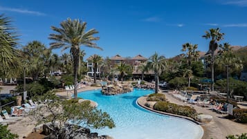 Un resort con piscina central rodeada de palmeras y sillas de descanso.