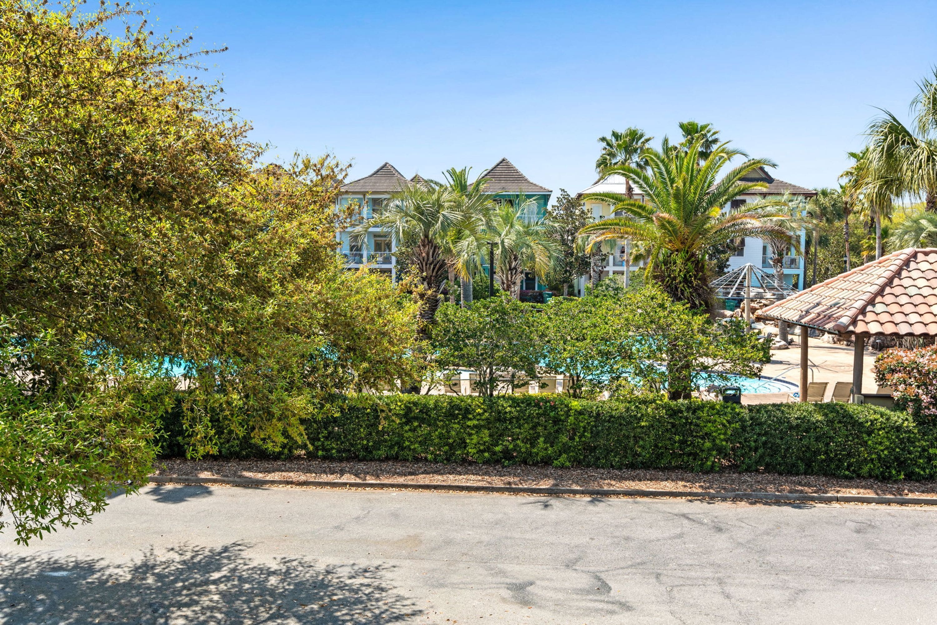 Un resort con edificios de varios pisos, piscina y exuberante vegetación.