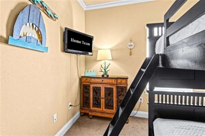 A room with a TV displaying 'Home Team,' a wooden cabinet, a lamp, and a staircase. - Mins From Beach Sleeps 17 Outdoor Seating (Destin)