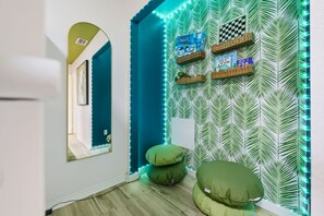 Un pasillo con un muro espejado, un juego de mesa a cuadros y una pared con diseño de hojas.