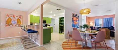 Un espacio moderno de sala con comedor, cocina y un juego de sofás.