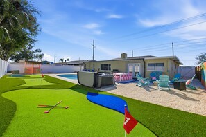 Ein Garten mit Pool, Kunstrasen und Gartenmöbeln.