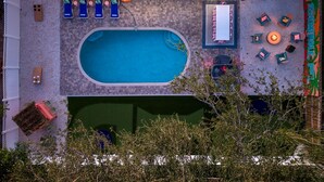 Vist des de dalt d'una zona de piscina amb gandules i una zona de barbacoa.