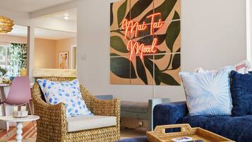 A living room with a wicker chair, a blue sofa, and a wall art piece.