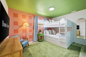 Una habitación con literas, un escritorio, una silla, una lámpara y una mesita.