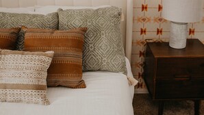 A bedroom with a bed, pillows, a nightstand, a lamp, and a wall with a geometric pattern. - Casa de Oro Saguaro Views Pool Hot Tub (Tucson)