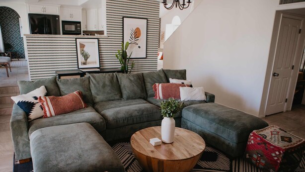 A living room with a sectional sofa, a round wooden coffee table, and a patterned rug. - Casa de Oro Saguaro Views Pool Hot Tub (Tucson)