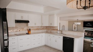 A modern kitchen with white cabinetry, a black dishwasher, and a tiled backsplash. - Casa de Oro Saguaro Views Pool Hot Tub (Tucson)