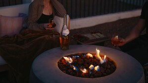 A round table with a fire pit in the center, surrounded by two people seated on a bench. - Casa de Oro Saguaro Views Pool Hot Tub (Tucson)