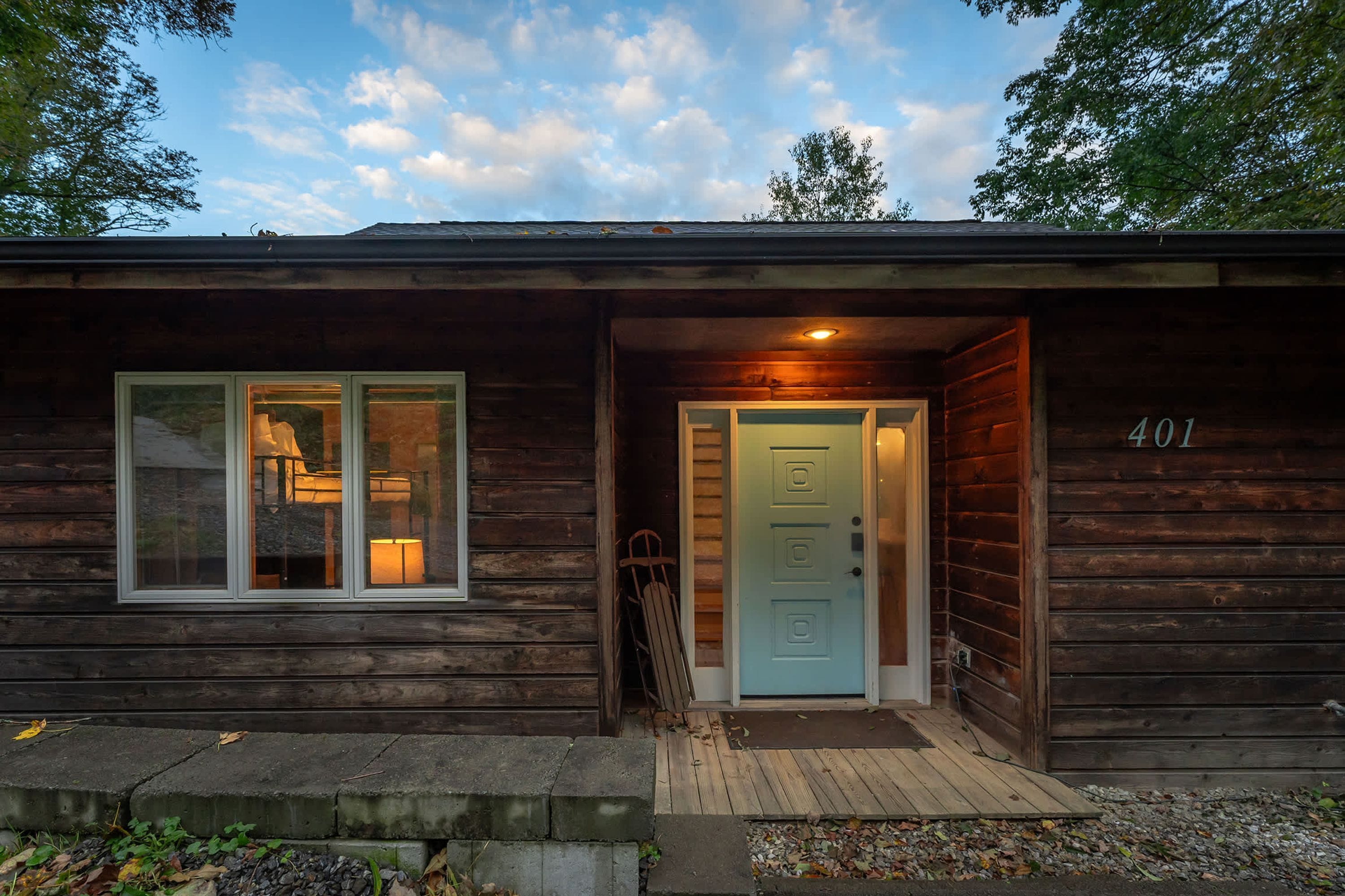 A wooden cabin with a single door and a window, a number '401' on the door, and a small porch area.