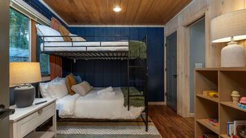 A bunk bed room with a desk, a lamp, and a bookshelf.