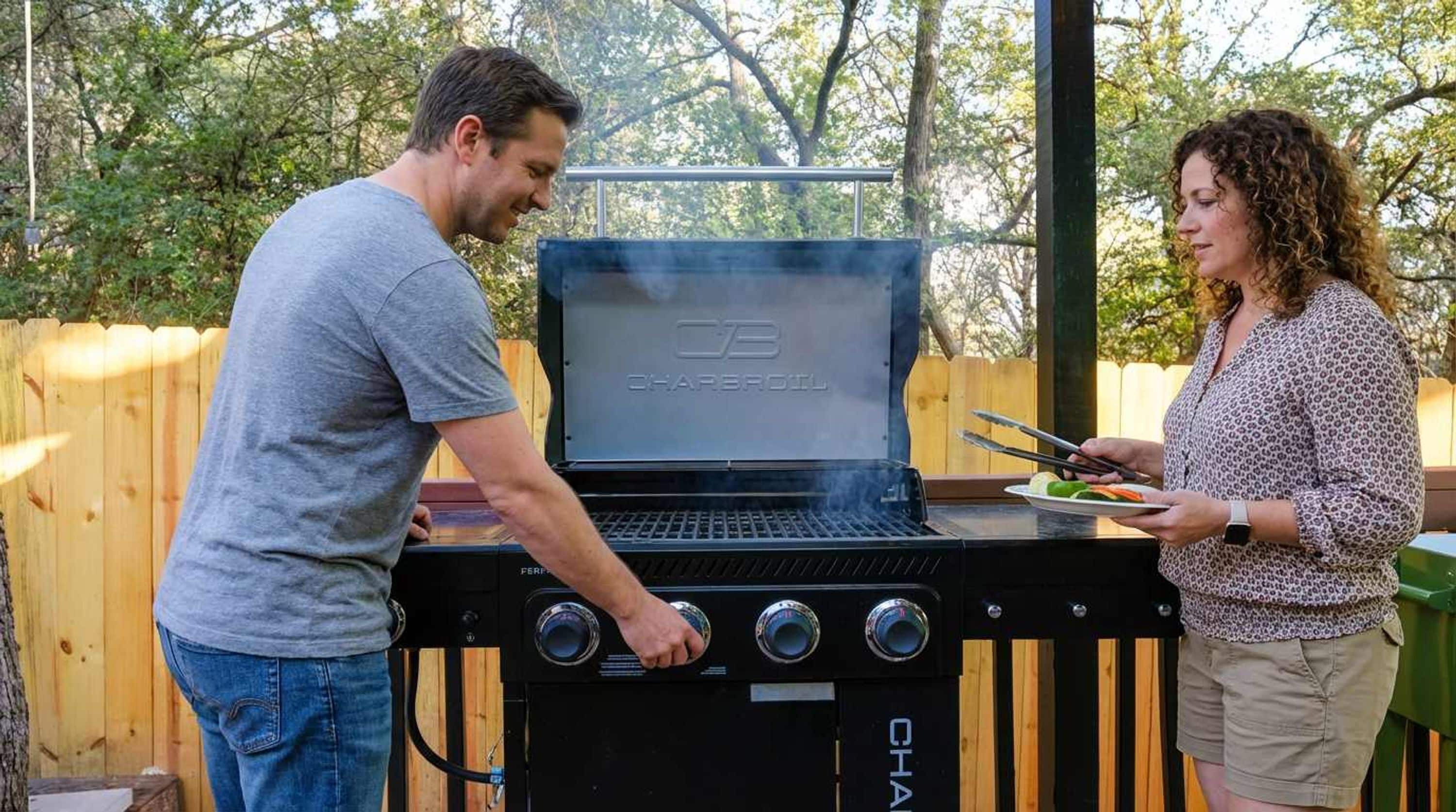 A man and a woman grilling outdoors with a Char-Broil grill.