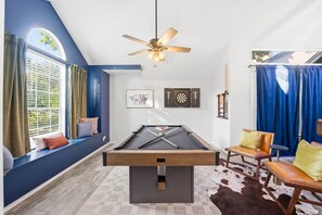 A pool table in a room with a ceiling fan, a window with blinds, and a blue curtain. - Resort Style Backyard Arcade Games Hot Tub (San Antonio)
