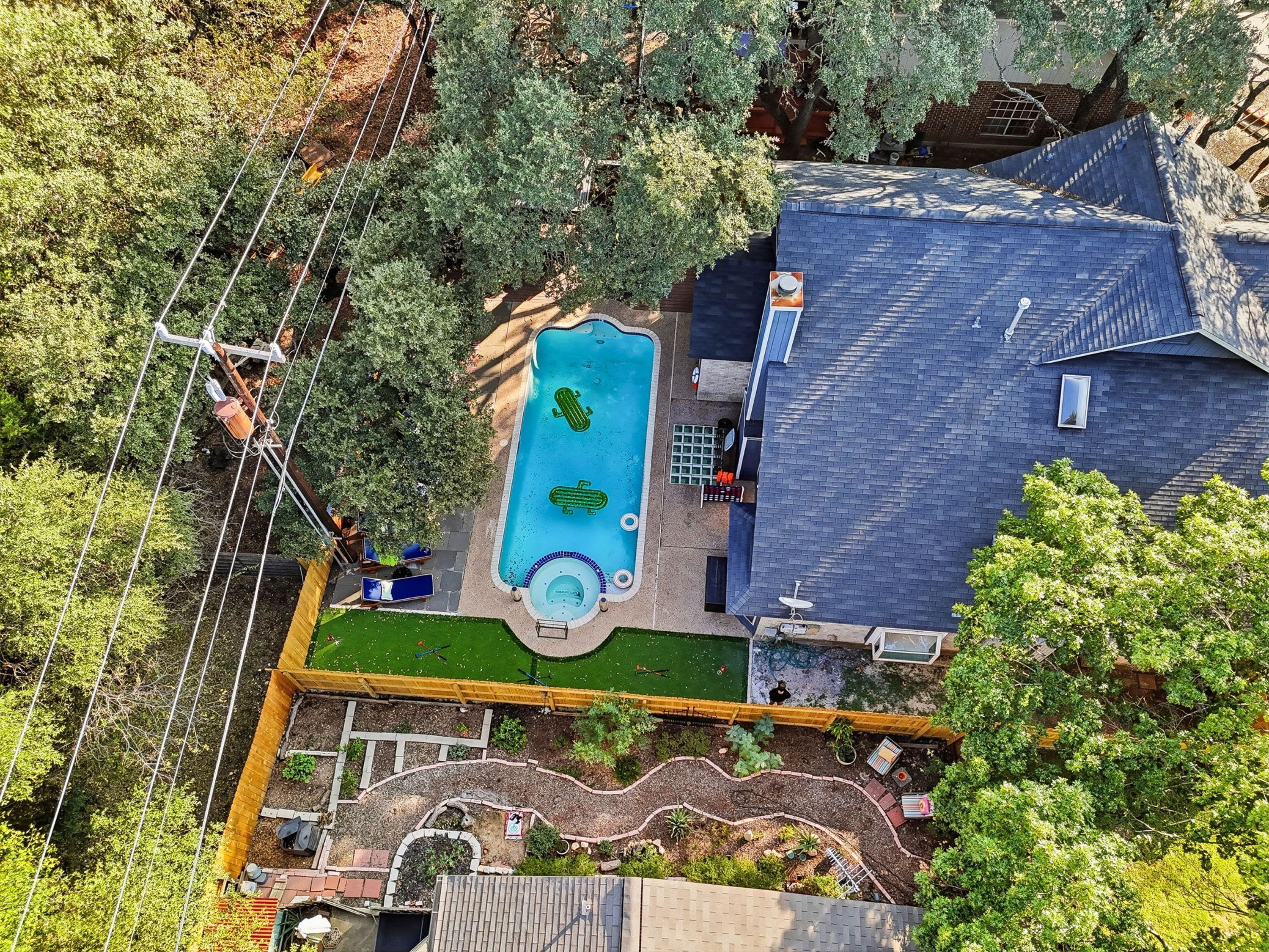 Vue aérienne d’une propriété résidentielle dotée d’une piscine, d’un jardin clôturé et d’une maison à toit en pente.