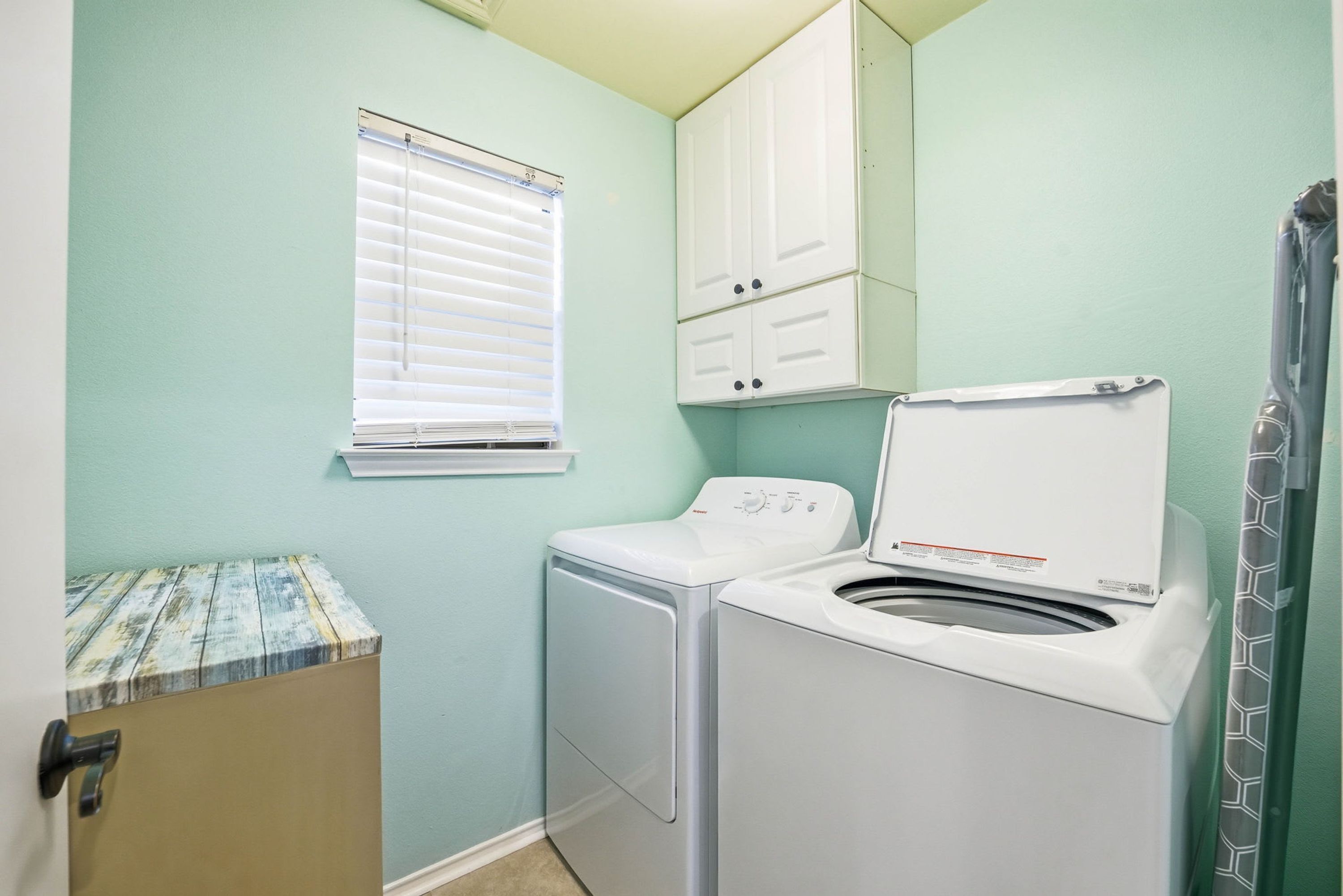 A laundry room with a washing machine, dryer, and a small cabinet.