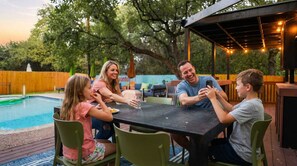 A family dining at an outdoor table with a pool in the background.