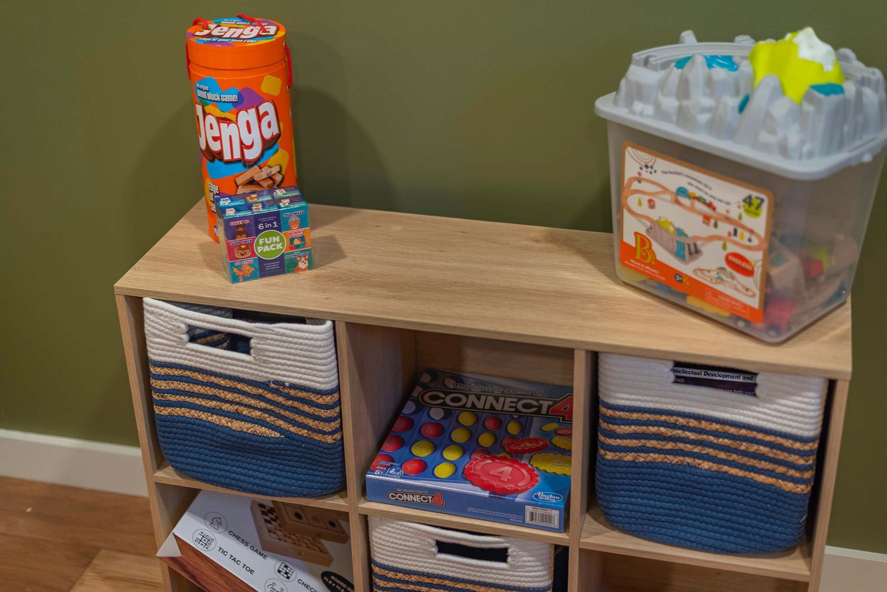 Une étagère contenant divers jeux pour enfants, notamment Jenga, Connect 4 et un jeu avec un ensemble « 6 en 1 ».