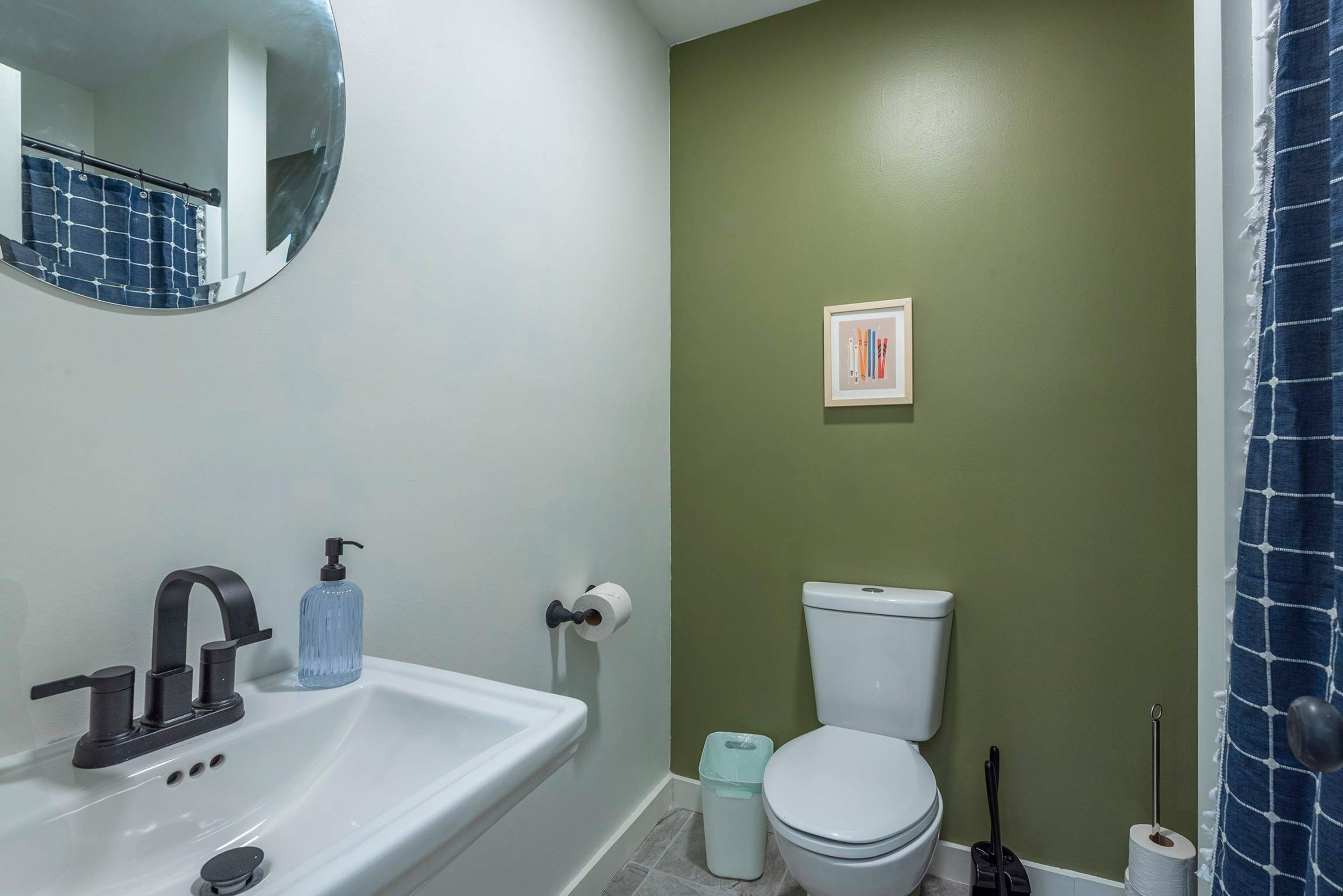 Un baño con lavamanos blanco, un espejo, inodoro y cortina de ducha.