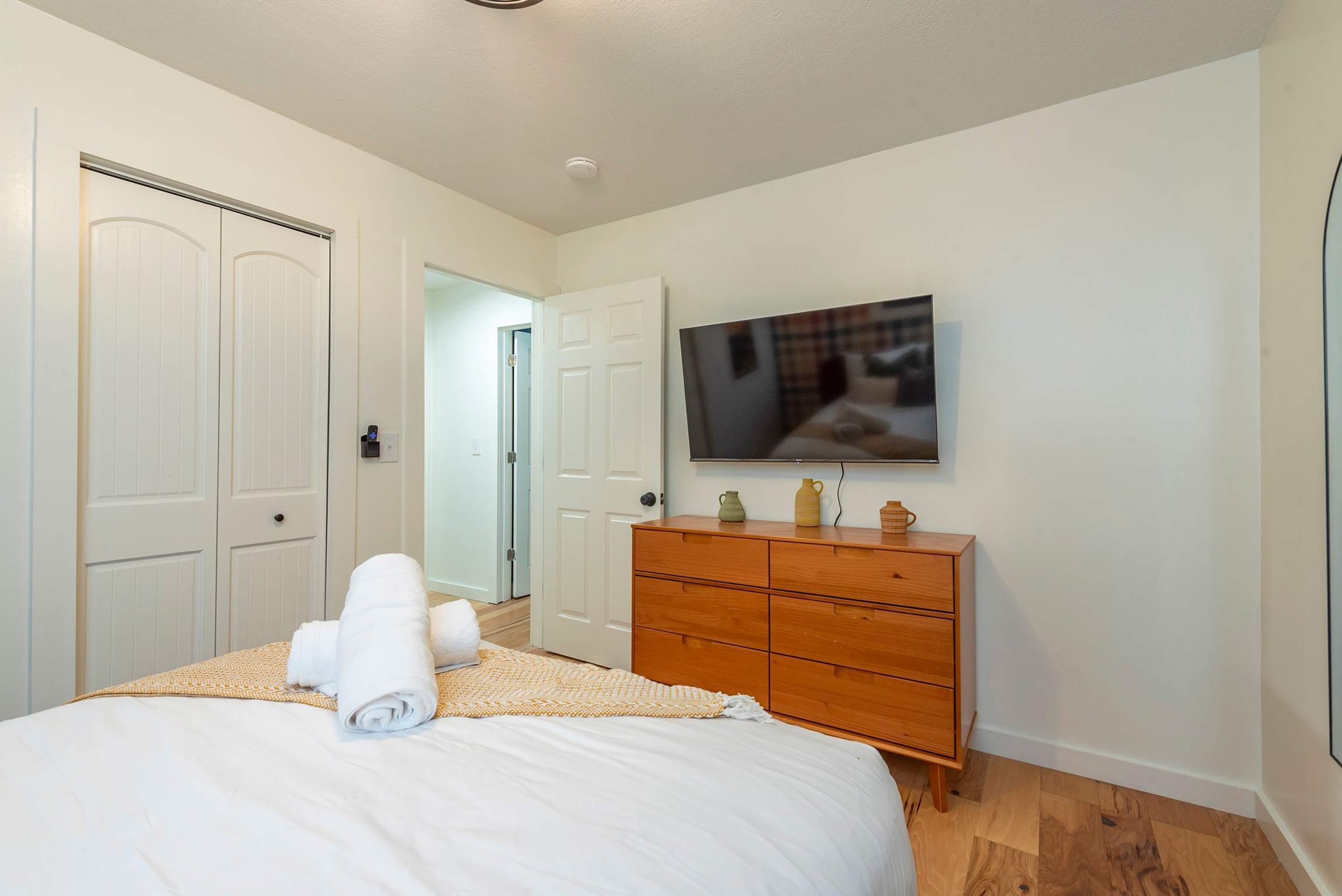A bedroom with a bed, a dresser, a television, and a door.
