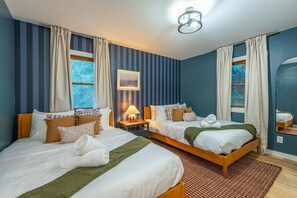 A hotel room with two beds, striped walls, a window with curtains, a lamp, and a framed picture on the wall. - Expansive Deck Sleeps 16 Hot Tub Game Room (Fairview)