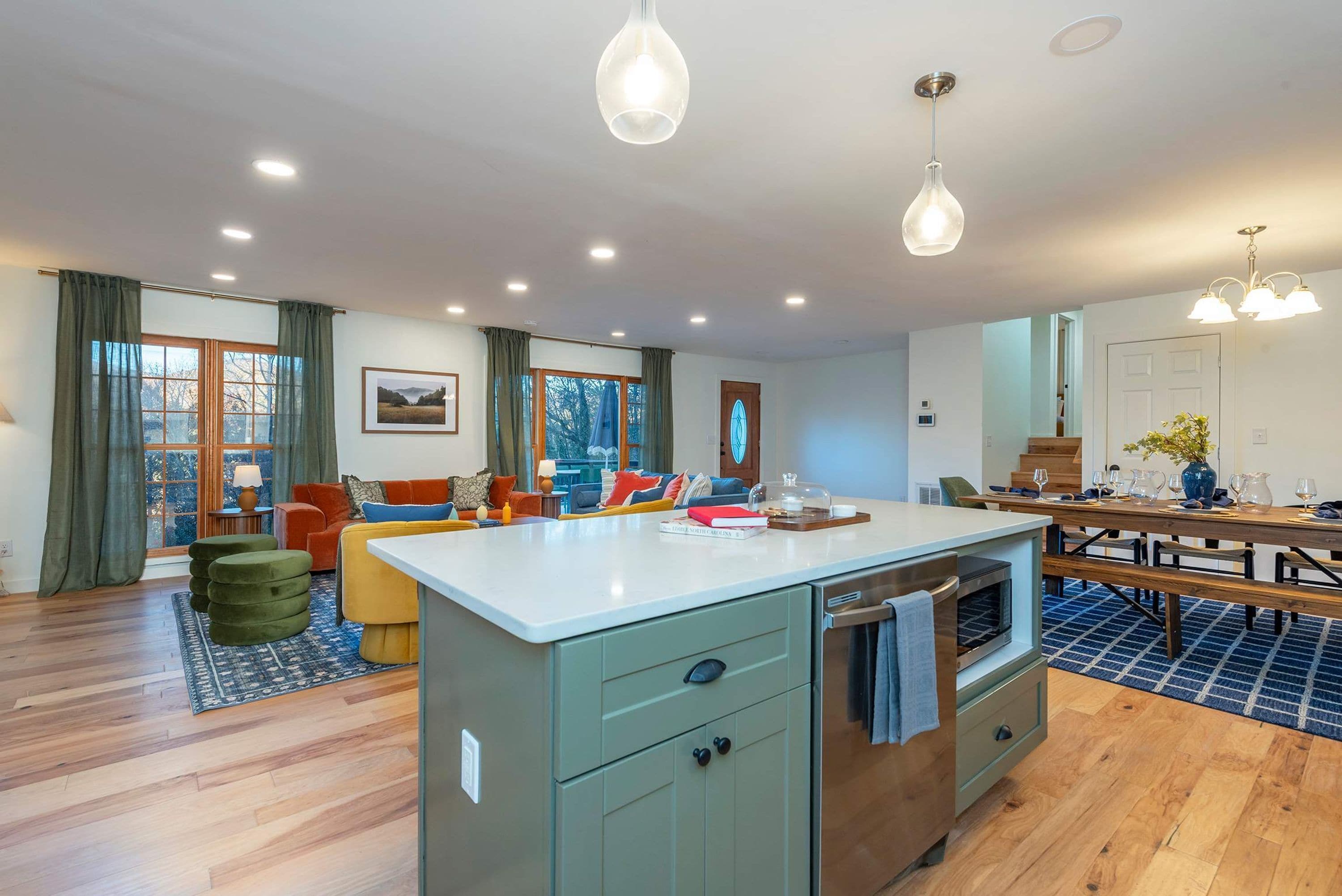 A modern kitchen with a central island, wooden flooring, and a dining area with a table and benches.