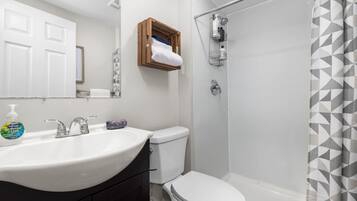 A bathroom with a white sink, a toilet, and a shower area.