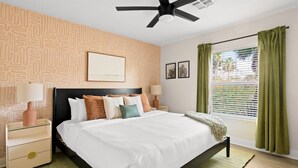 A modern bedroom with a bed, nightstands, a ceiling fan, and a window with curtains. - The Sunkiss Pickleball Heated Pool Hot Tub (Scottsdale)