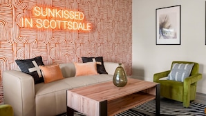 A modern living room with a patterned wallpaper, a sofa with cushions, a coffee table, and a green armchair. - The Sunkiss Pickleball Heated Pool Hot Tub (Scottsdale)