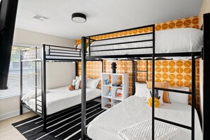 A bunk bed room with a white and orange patterned wall, a white shelf unit, and a black metal frame. - The Sunkiss Pickleball Heated Pool Hot Tub (Scottsdale)
