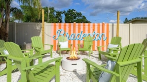 A patio area with green Adirondack chairs, a fire pit, and a decorative sign that reads 'Bradenton.' - Suncourt Retreat Sports Court Pool Hot Tub (Bradenton)