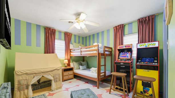 A bunk bed room with a ceiling fan, arcade games, and a tent-like bed. - Suncourt Retreat Sports Court Pool Hot Tub (Bradenton)