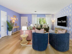 A living room with a sofa, two armchairs, a TV, and a plant. - Suncourt Retreat Sports Court Pool Hot Tub (Bradenton)