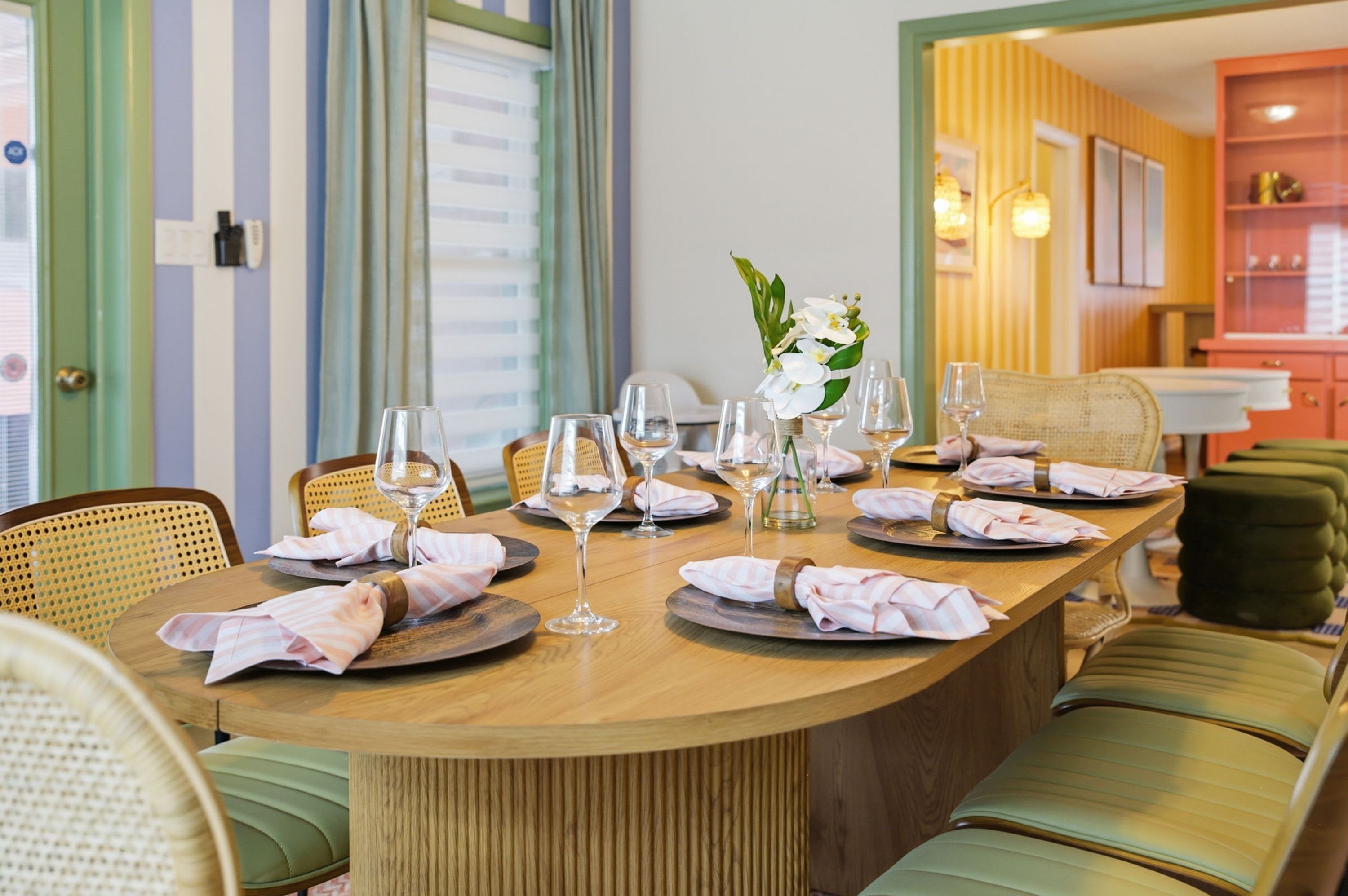 A dining table set for six with wine glasses, plates, and a vase of flowers.