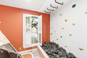 A room with a white window, orange walls, and a white ceiling. - Ultimate Backyard Pool Game Room Kid s Room (San Antonio)