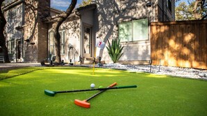 A well-maintained lawn with a putting green, a flag, and golf equipment. - Ultimate Backyard Pool Game Room Kid s Room (San Antonio)