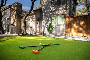 A well-maintained lawn with a putting green, a flag, and golf equipment. - Ultimate Backyard Pool Game Room Kid s Room (San Antonio)