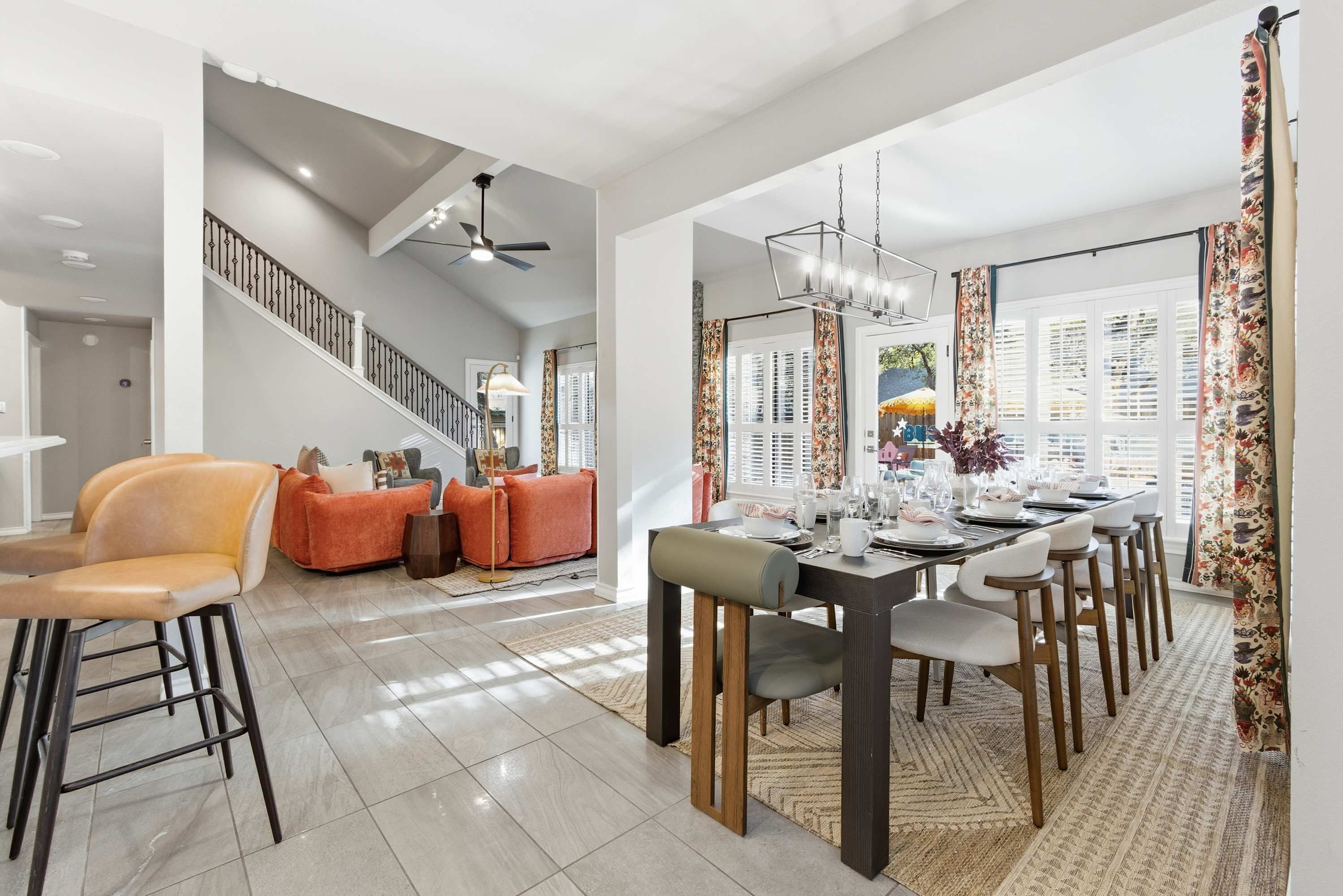 A spacious dining area with a high ceiling, a staircase, and a view of the outdoors.
