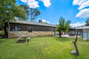 A rustic building with a stone facade and a metal roof, a picnic table, and a covered outdoor seating area. - 2 Home Getaway-pool-hot Tub-pickleball Court (Fredericksburg)