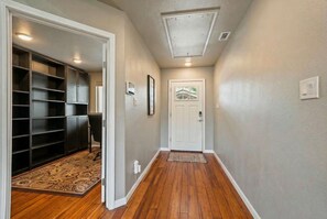 A hallway with a wooden floor, a door at the end, and a built-in closet with shelves. - 2 Home Getaway-pool-hot Tub-pickleball Court (Fredericksburg)