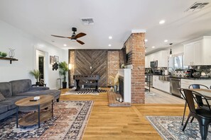 A modern living room with a sofa, coffee table, and a fireplace. - The Glow-up House Pool Spa Glam Room (Phoenix)