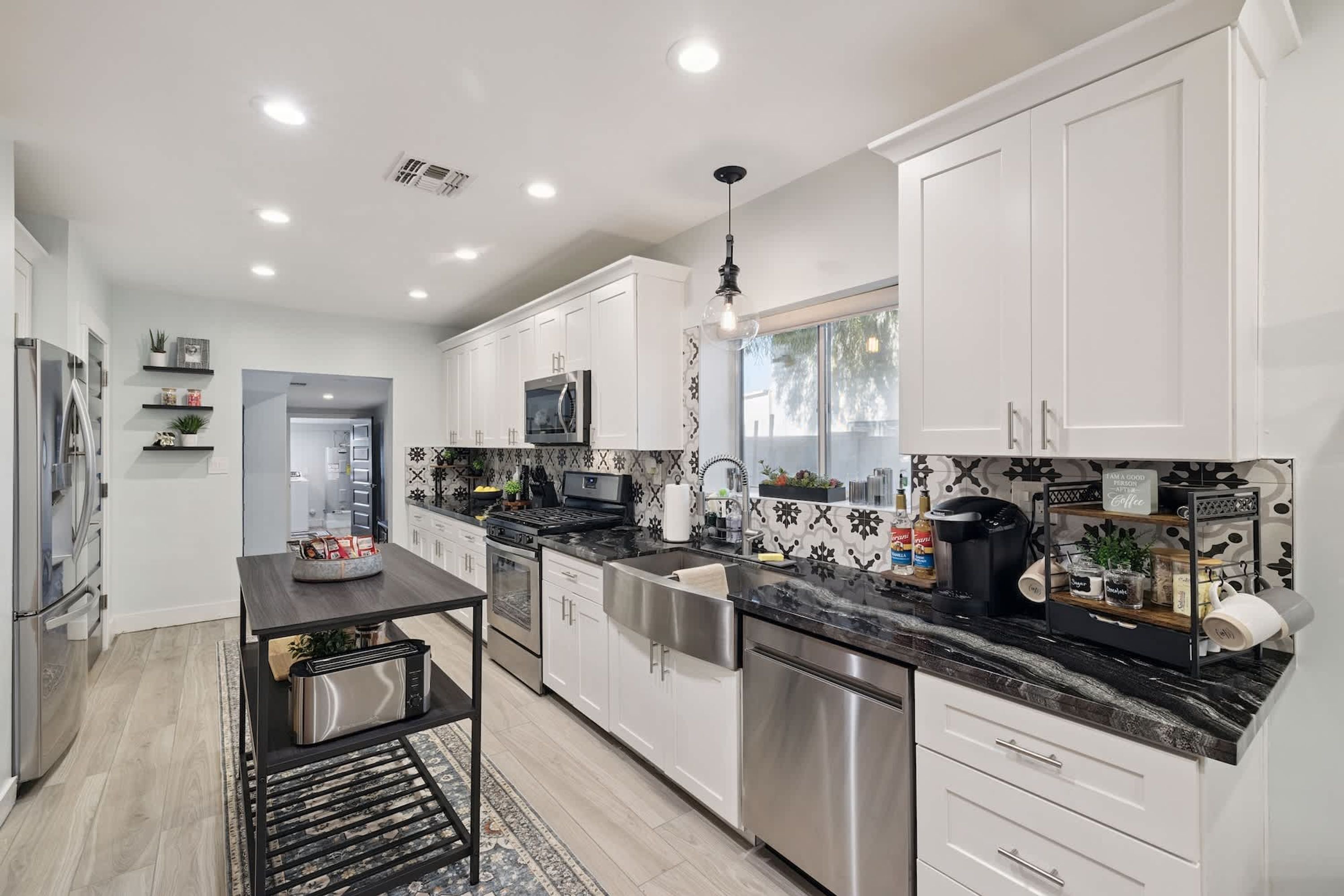 A modern kitchen with stainless steel appliances, white cabinetry, and a black countertop.